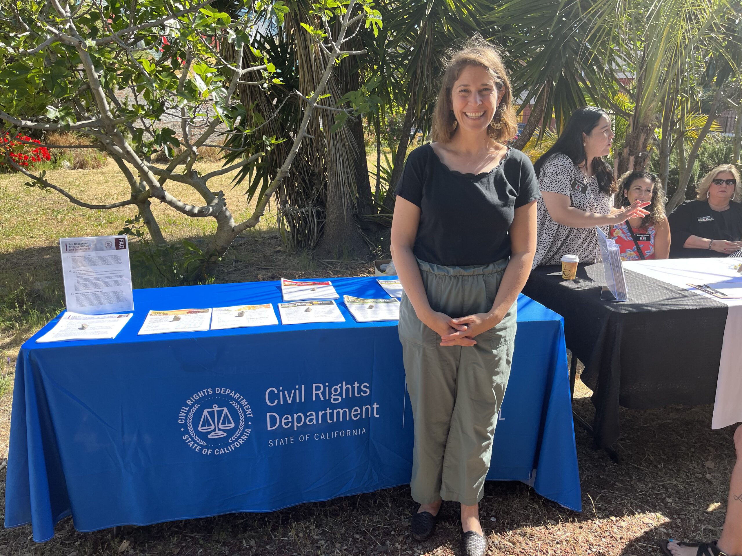 Lily Harvey at an outreach event. She is in front of a table with the CRD logo on it