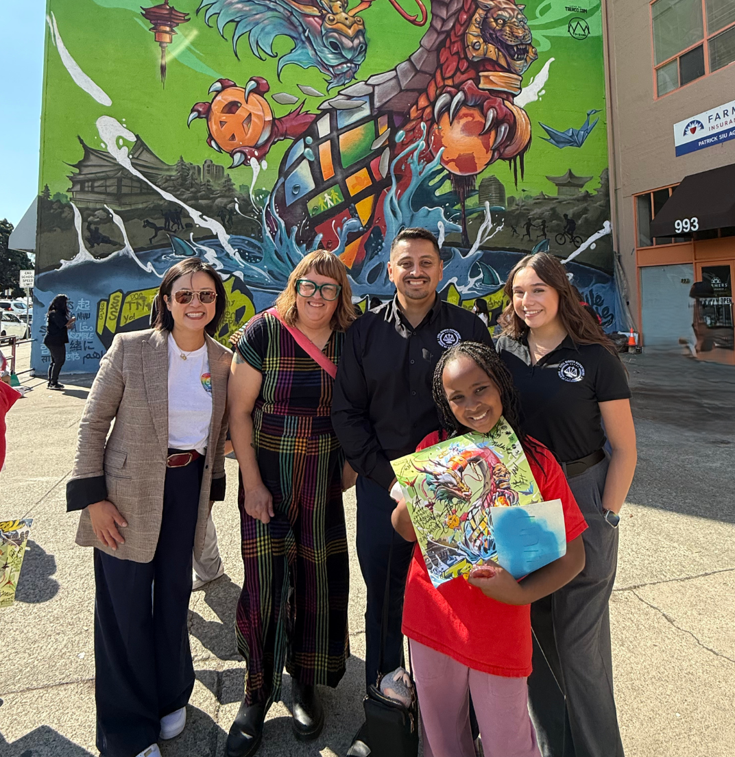 Image of CRD Staff in front of mural, at an outreach event.